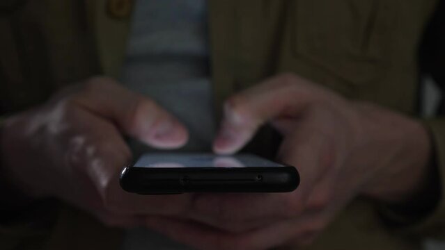 close up of young male checking on his phone during the night, selective focus. Browsing social networks.