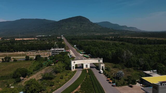 Big white gateway for Bokor Hill Station on the long road in Bokor National Park with the high green mountains of Cambodia in the background. Wide panning drone shot