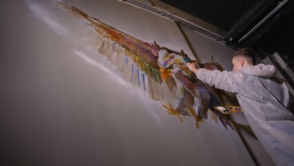 Artist designer draws an eagle on the wall. Craftsman decorator paints a picture with acrylic oil...