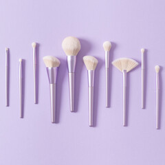 Set of different make up brushes, violet make up tools on violet background. Professional make up brushes for visagist. Cosmetic composition. Magazine, cosmetics store, social media. Square