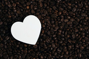 White heart on the background of roasted coffee beans.
