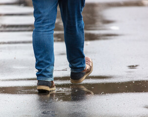Legs of a man walking on a wet road in a park