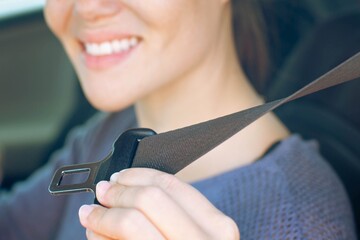 A female driver buckling her seat belt before driving her car. Road safety.