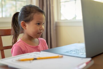 A child learning at home at her computer, online class. Kids educational tv.