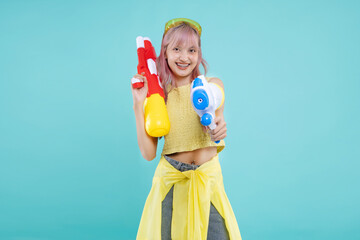 Happy Asian beautiful girl holding a water gun on pastel green mint color background. Girl plays water in Songkran festival. Thai New Year's national holiday.