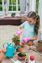 Kids learning gardening outdoors. Girl planting flowers in pots at greenhouse. Kids taking care of...