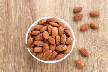 Almonds in bowl on wooden table.  Close up. Selected focus
