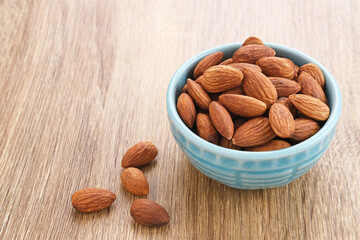Almonds in bowl on wooden table.  Close up. Selected focus

