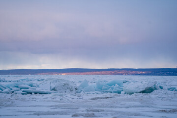 Obraz premium Blue Ice Chunks on Lake Michigan - Frozen Lake with snow, beautiful colorful sky, and clouds in the background