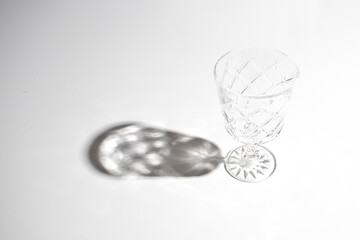 Empty glass with beautiful hard shadow on white bakground.