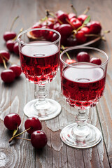  Liqueur in small glasses on the wooden table with fresh cherries