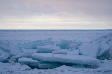 Obraz premium Blue Ice Chunks on Lake Michigan - Frozen Lake with snow, beautiful colorful sky, and clouds in the background