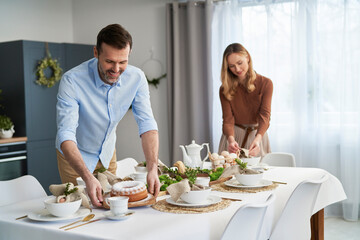 Caucasian couple setting table with an easter cake