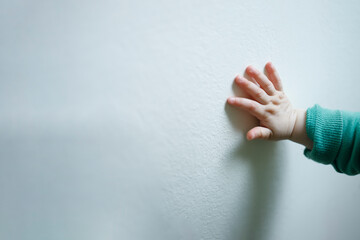 A child hand on a white wall, humanitarian help concept