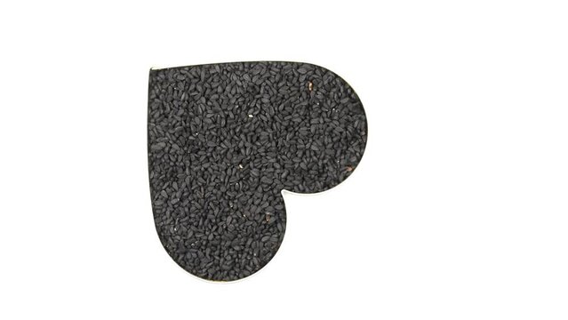 black cumin seeds in a heart shape on a turn table