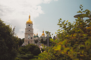 Fototapeta na wymiar Bell tower of Sant Sophia cathedral in Kiev, Ukraine, viewed from distance through the bushes on a sunny day in summer