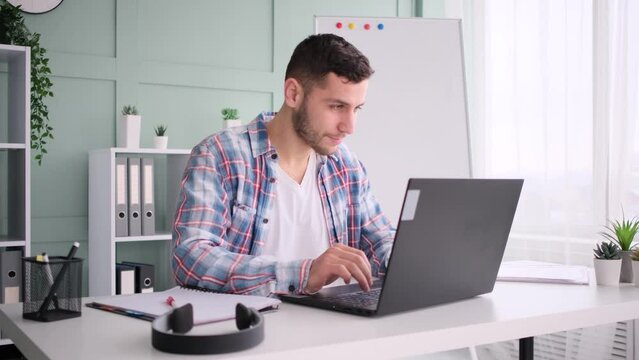 Caucasian man and smilling working in home office, using laptop