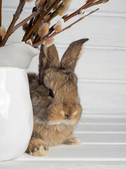 A small gray rabbit is a symbol of the Easter holiday on a light wooden background