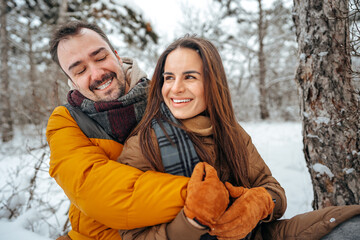Young couple in love outdoor in snowy winter forest.