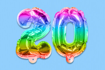 Rainbow foil balloon number, digit twenty on a blue background. Birthday greeting card with inscription 20. Anniversary concept. Top view. Numerical digit. Celebration event, template.