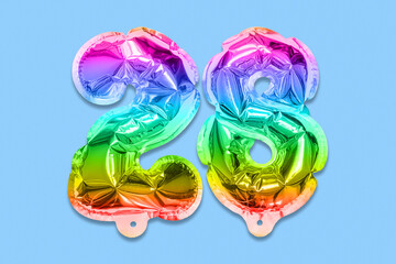 Rainbow foil balloon number, digit twenty eight on a blue background. Birthday greeting card with inscription 28. Top view. Numerical digit. Celebration event, template.