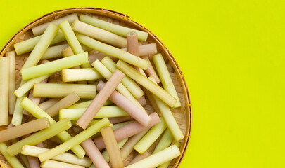 Lotus stems in bamboo plate on green background.