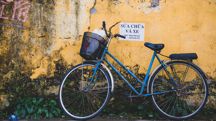 Fototapeta na wymiar old Blue bicycle in front of yellow wall