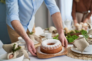 Close up of caucasian couple setting table with an easter cake