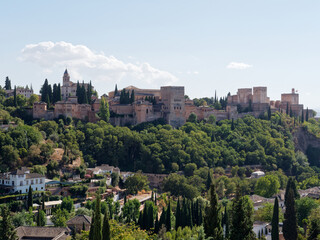 Fototapeta na wymiar Panoramic view of Alhambra in Granada with the Sacromonte neighborhood below. Moorish Architecture. Unesco Spain. Travel in time and discover history. Amazing destinations for holidays. 