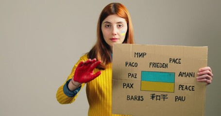 Girl holds up placard with lettering for peace and stop the war in Ukraine