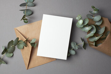 Invitation or greeting card mockup with envelope and natural eucalyptus twigs.