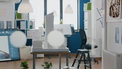 Nobody in architectural office with building model and 3d construction plan, tools used for urban project and property development. Empty space with maquette and blueprints design.