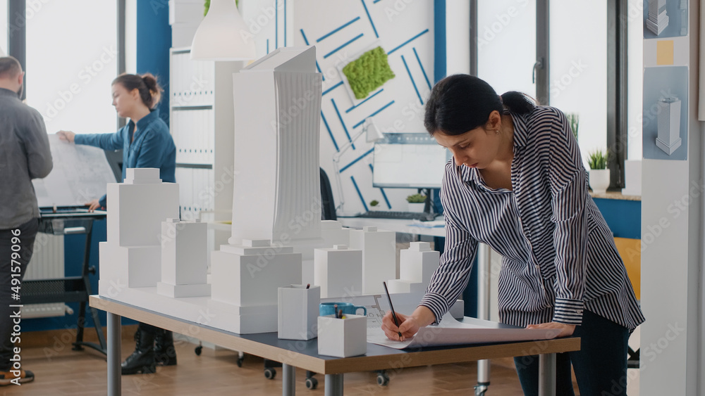 Poster woman architect analyzing blueprints plan on table to design building model and maquette. engineer w
