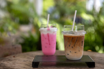 Glass iced coffee on wood table green nature background,Iced latte coffee.