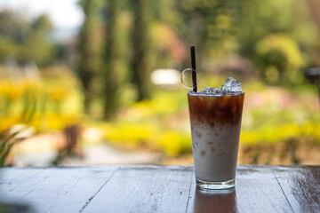 Glass iced coffee on wood table green nature background,Iced latte coffee
