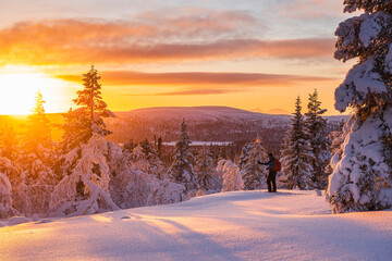Hiker in snowy forest at sunset