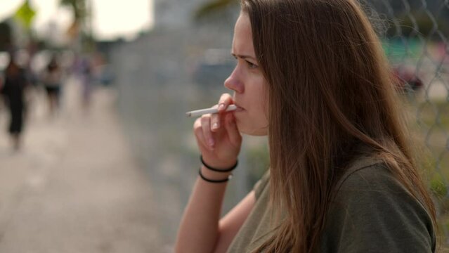 Young dissatisfied woman lights a cigarette