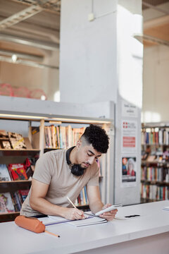 Male student taking notes in library