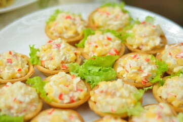 Waffle baskets with salad and stuffing with crab sticks, corn and eggs, soft focus. delicious picnic recipe