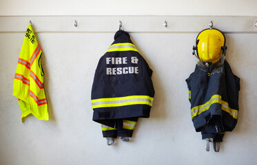 Its not the uniform that makes a hero. Firemans clothing hanging from a wall. - obrazy, fototapety, plakaty
