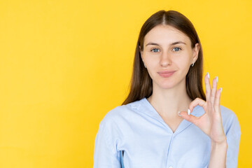 Positive answer. Smiling woman. Ok gesture. Pretty confident lady in casual shirt showing approving sign isolated yellow copy space.