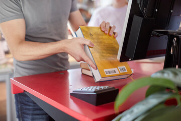 Male student scanning book in library