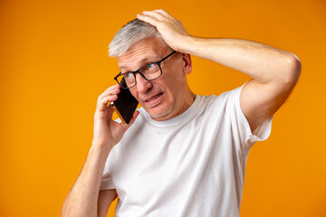 Concerned and troubled shocked senior man using smartphone