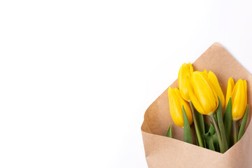 A bouquet of spring tulips with yellow flowers wrapped in kraft paper for a gift, isolated on a white background.