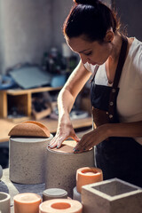Craftswoman working in her workshop making decorative concrete vase.
