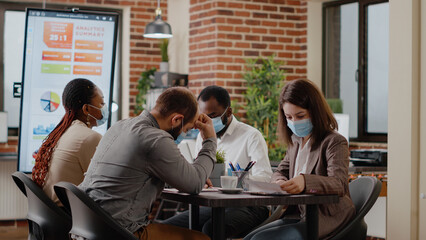 Team of diverse coworkers arriving at business meeting in office during covid 19 pandemic. Colleagues working together to plan marketing project and strategy for financial presentation.