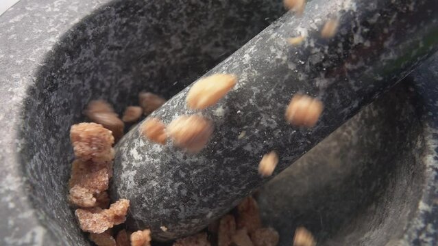 Large pieces of the sweet brown sugar are falling into the grey stone mortar
