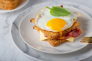 Sandwich with a fried egg, bacon, cheese and spinach