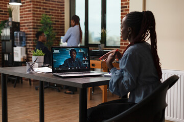 Businesswoman in remote videocall conference with executive officer while sitting at desk in office workspace. Financial advisor informing african american team leader about possible bankruptcy event.