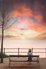 woman sitting on bench and looking at the sea